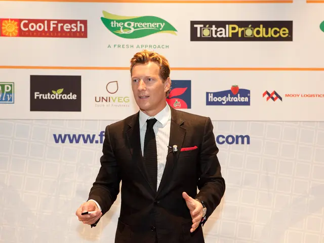 In this picture, we see the man in the black blazer is standing. He is holding something in his...